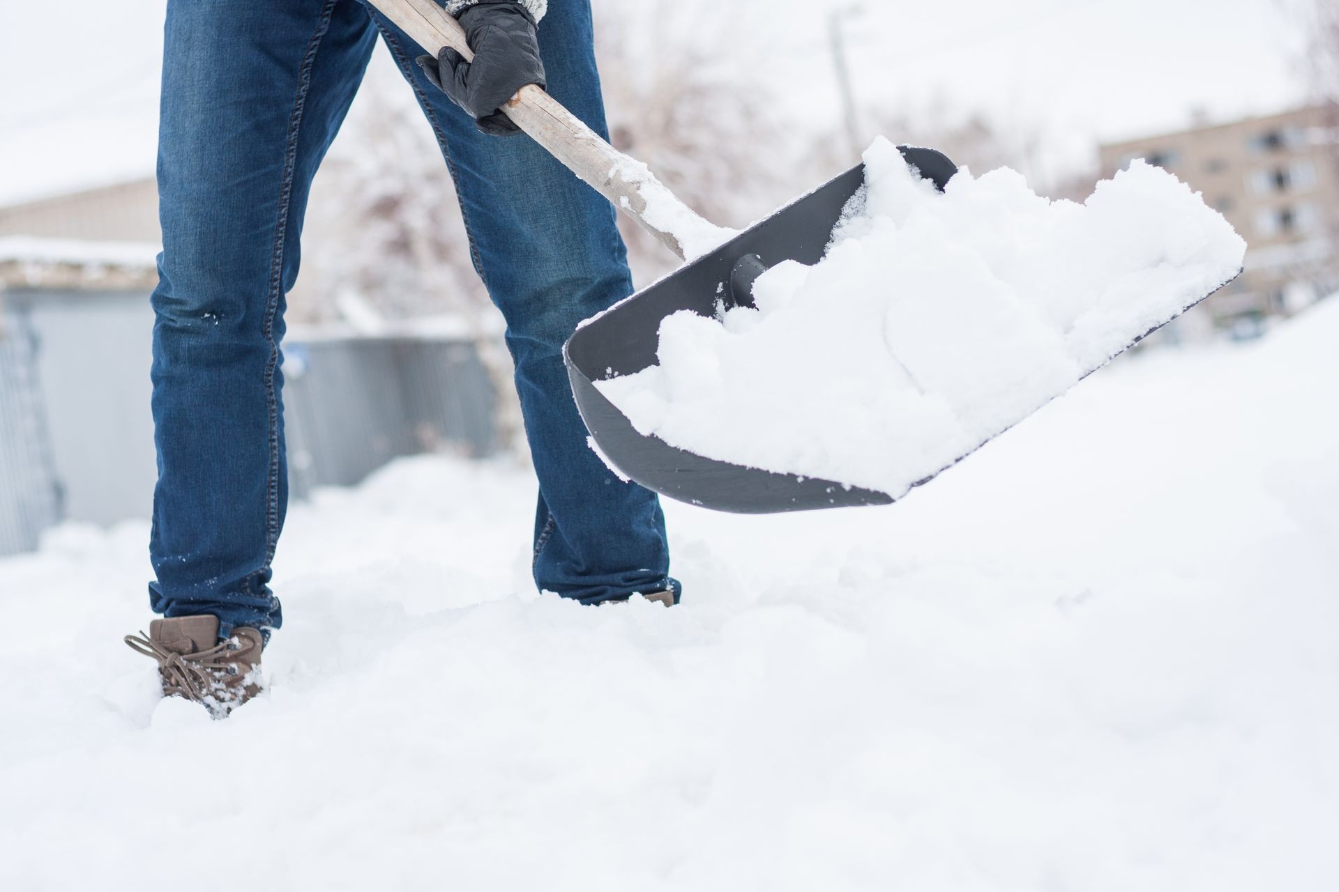 close up view of snow shovel with snow in man's hands. Man clean backyard of his house after blizzard. Spring snow cleaning.