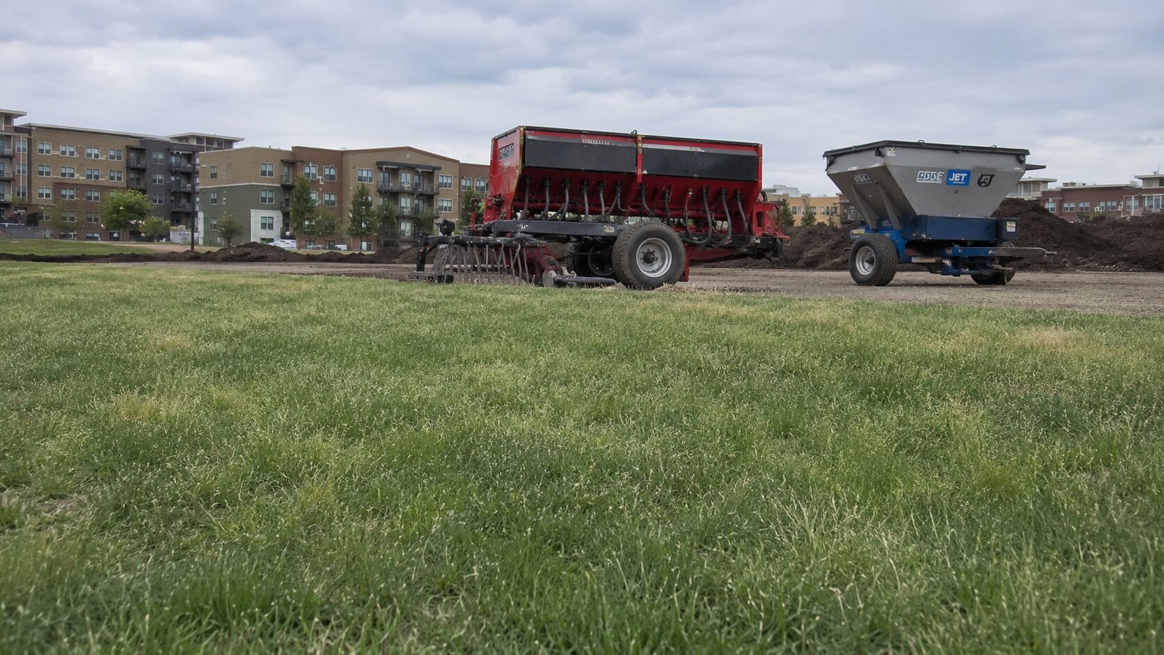 Seed spreader and site-prep equipment staged at an installation site